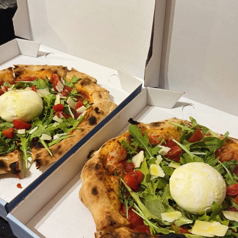 Pizza mit Burrata, Rucola und Cherrytomaten im Karton zum Mitnehmen